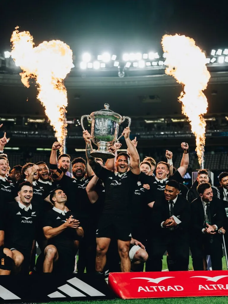 All Blacks players celebrate with the Bledisloe Cup trophy at Eden Park following their 50–19 victory over Australia in 2026.